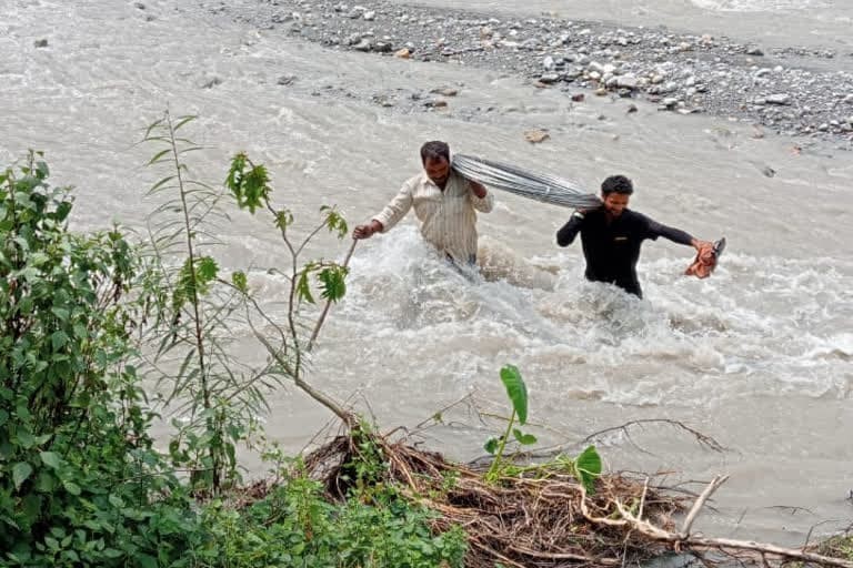 टिहरी गढ़वाल : बिजली विभाग मजदूरों की जान से 'खेल' रहा है ,मजदूर तारों का बंडल लादकर उफनती नदी पार कर रहे है